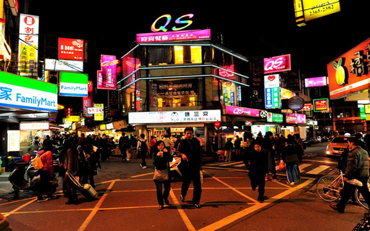 Chợ đêm Đài Bắc với biển hiệu neon rực rỡ, hàng quán đông đúc và du khách đi lại.